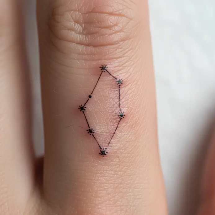 An ultra-fine single needle tattoo of the Cancer constellation placed along the side of a person's finger.