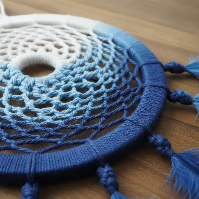 A dreamcatcher where the web and fringe are made from a single cord dyed in a soft blue-to-white ombre gradient.