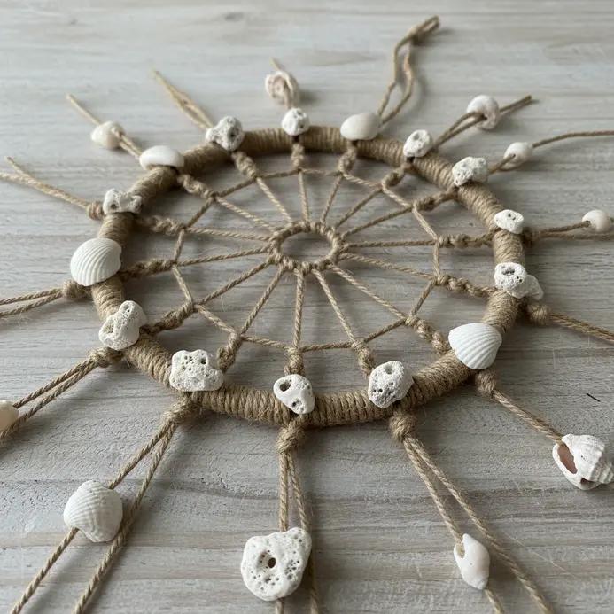A natural dreamcatcher made with knotted hemp cord and adorned with tiny collected seashells and sand dollars.