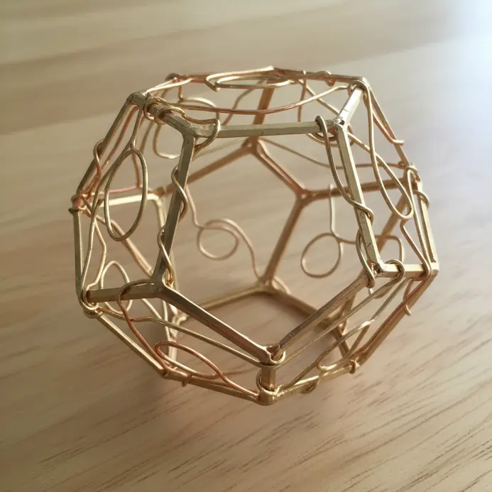 A contemporary dreamcatcher featuring interlocking geometric shapes formed from gold wire.