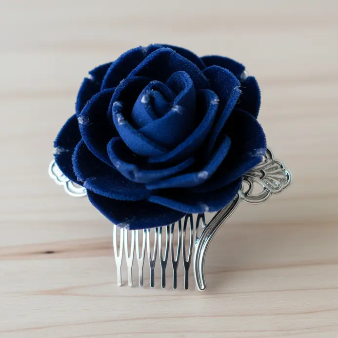 A silver hair comb holding a single, plush midnight blue velvet flower.