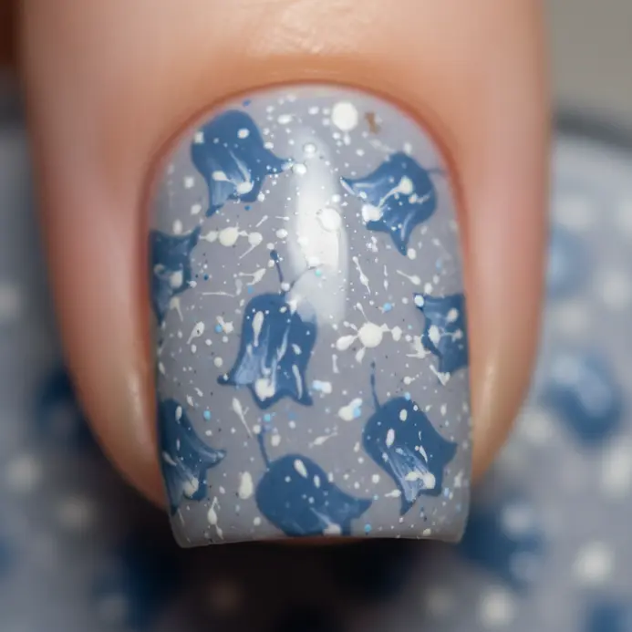An abstract pattern of bluebell shapes created with speckled blue and white polish on a grey base.