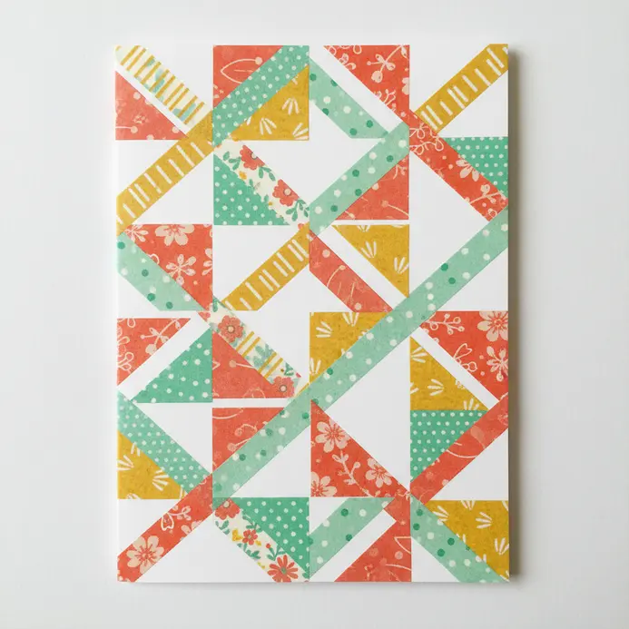 A bright greeting card decorated with thin, colorful strips of patterned washi tape arranged in a clean design.