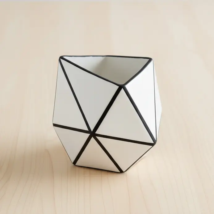 A modern pinch pot with sharp, triangular facets for holding pens and pencils.
