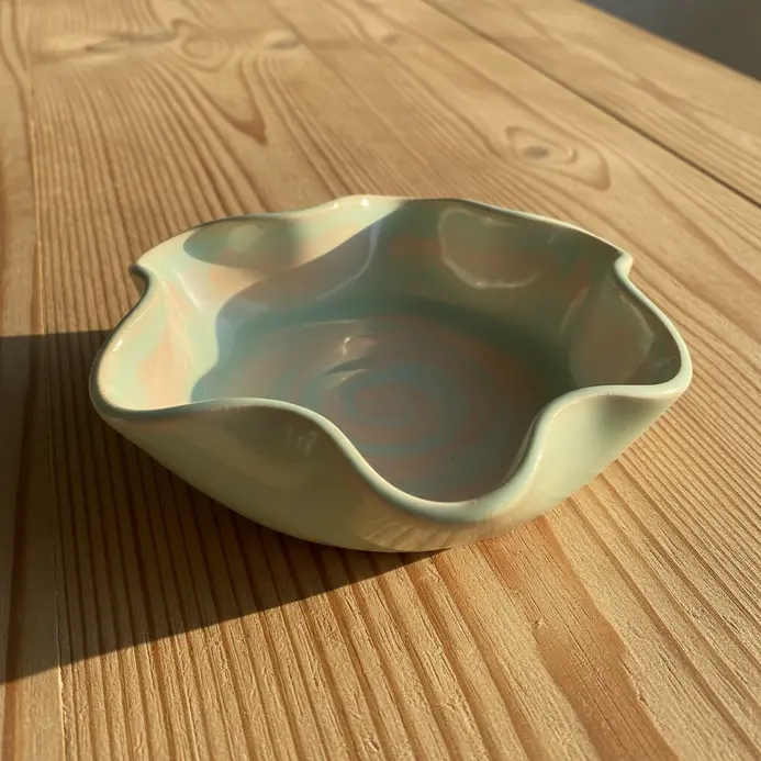 A wide, shallow pinch pot with a carefully shaped, wavy scalloped edge.