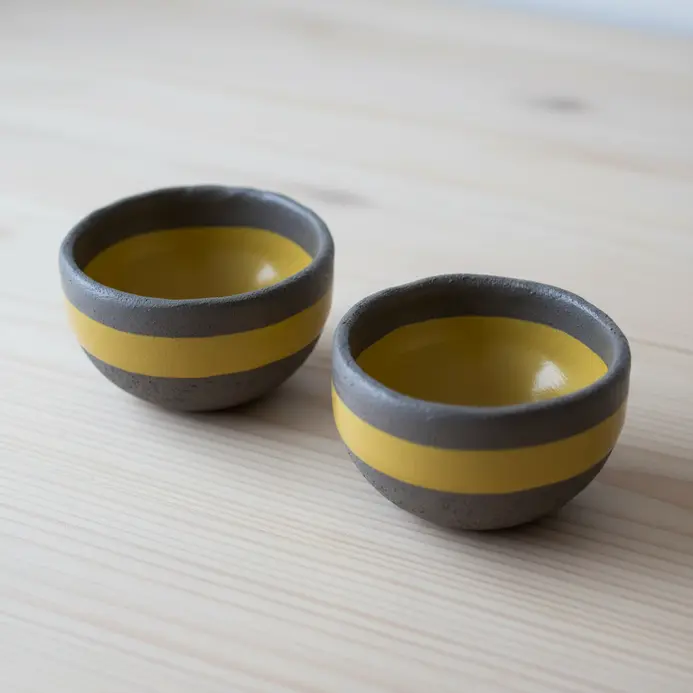 A set of two miniature pinch pot bowls with glaze neatly applied to the rim.