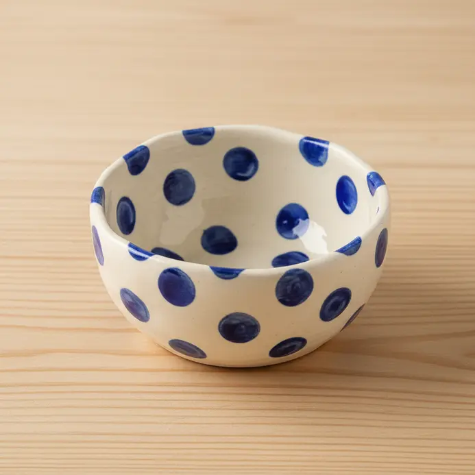 A colorful clay bowl with a playful pattern of painted polka dots.