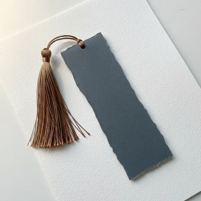 A slender, rectangular bookmark with a soft matte finish in slate grey, attached to a silk tassel.
