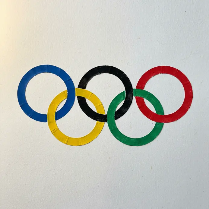 Five interlocking rings made from paper plates painted blue, black, red, yellow, and green.