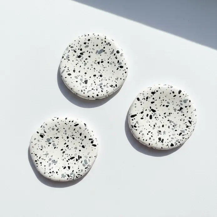 Three irregularly shaped clay pieces in white, covered with small black and gray speckles.