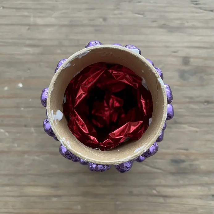 A child looks through a kaleidoscope made from a paper towel roll.