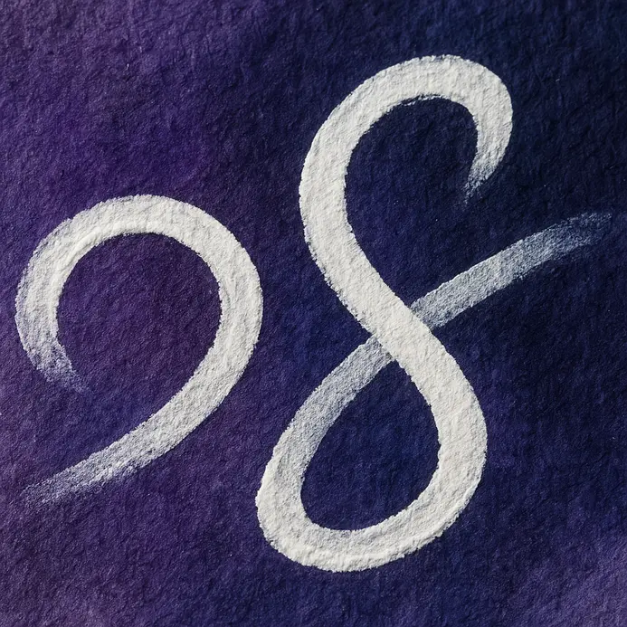 A small brush adds a bright white ink highlight along a letter's edge.