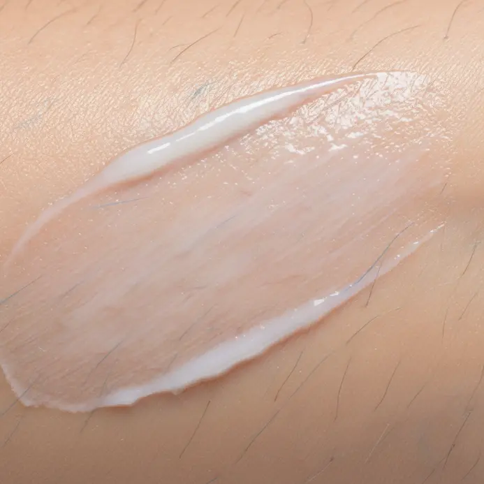 A person applying a simple, unscented moisturizer to their forearm where a tattoo is planned.