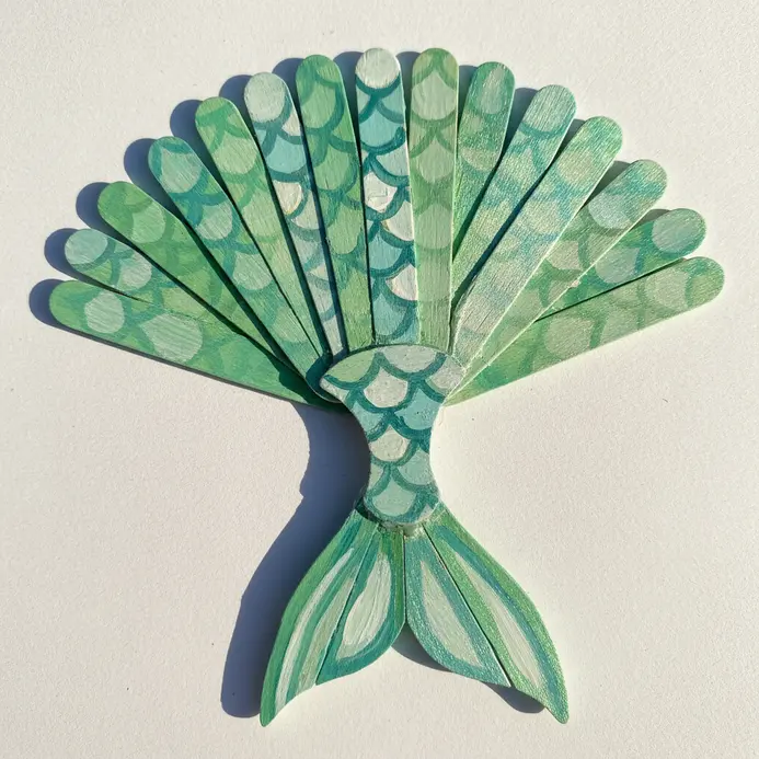 Popsicle sticks glued into a fan shape and painted with shimmering mermaid scales.