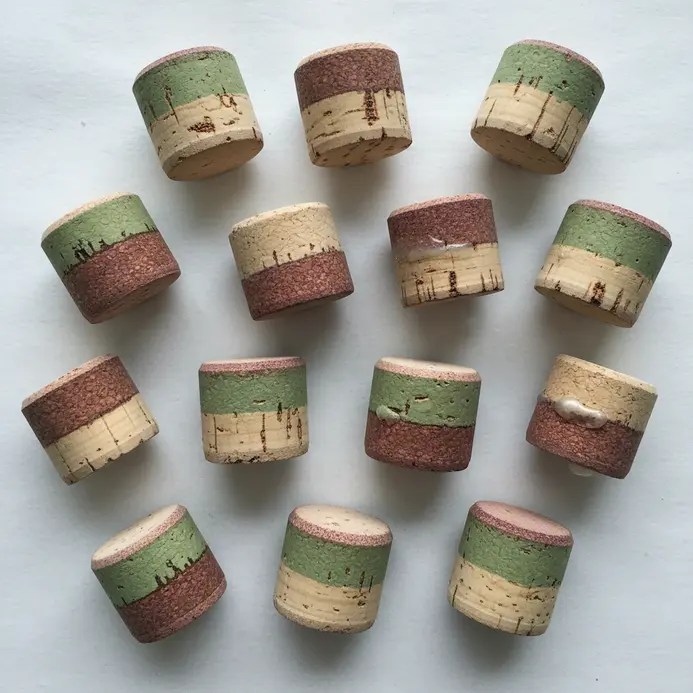Several garden markers made from wine corks sliced in half and stacked, with herb names written on the sides.