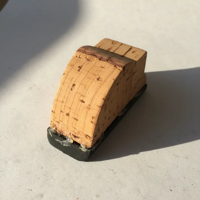 A single large wine cork cut into a wedge shape and sanded smooth, used to hold a door open.