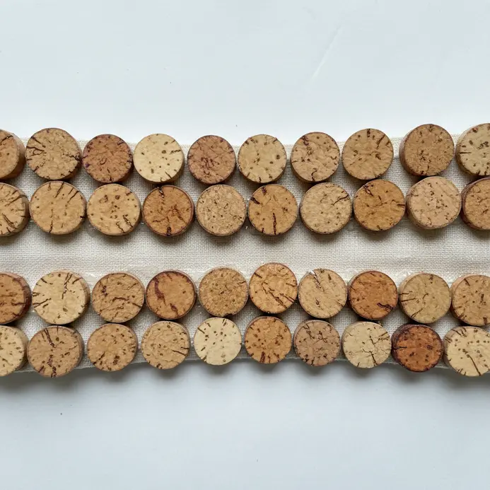 The bottom edge of a fabric lampshade trimmed with a band of thinly sliced wine cork rounds.