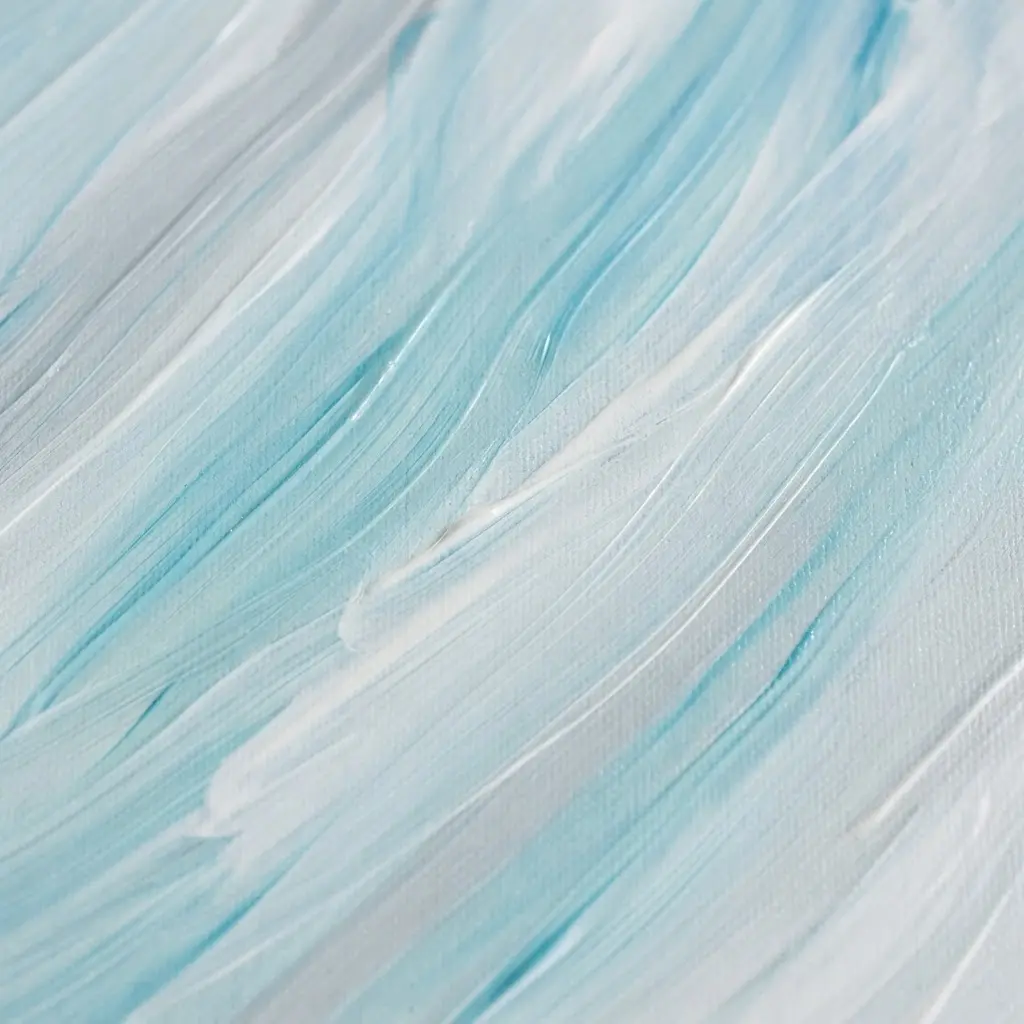 Several synthetic brushes rest in clean water beside a folded cloth and a palette with blue paint.