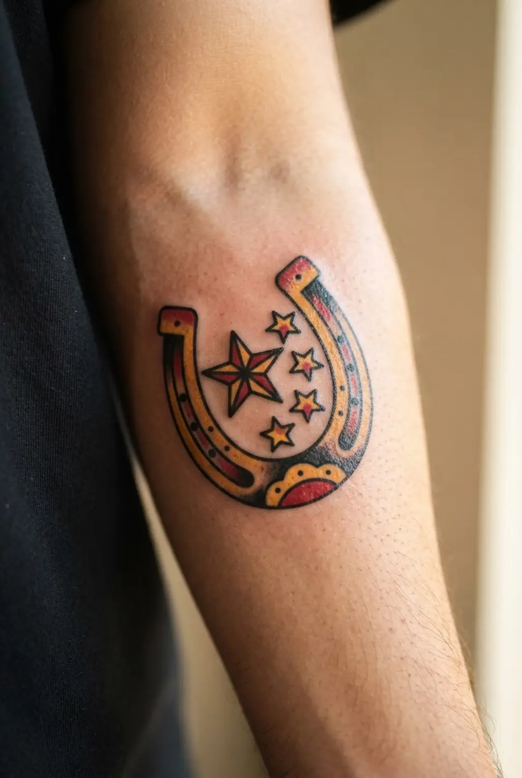 Lucky horseshoe tattoo beside yellow stars, red details, and bold black outlines in American traditional tattoo style.