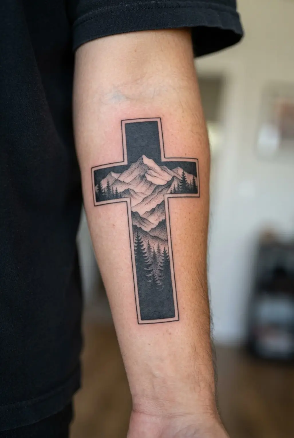 A mountain silhouette sits inside a tall forearm cross with pine trees, layered ridges, and solid black sky.