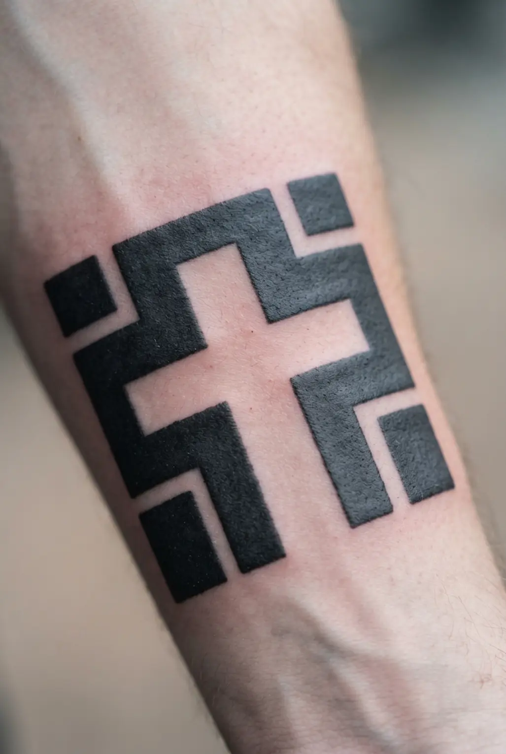 A geometric cross shape appears on the forearm through crisp negative space surrounded by black angular sections.
