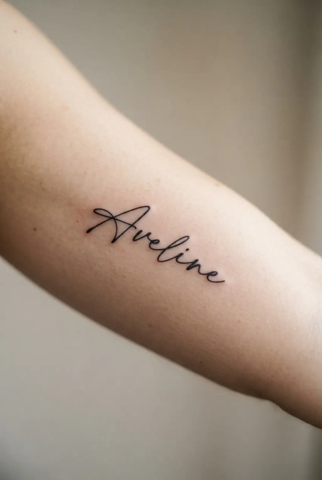Black and white tattoo ideas featuring a script signature on the inner bicep with smooth lettering and fine lines.