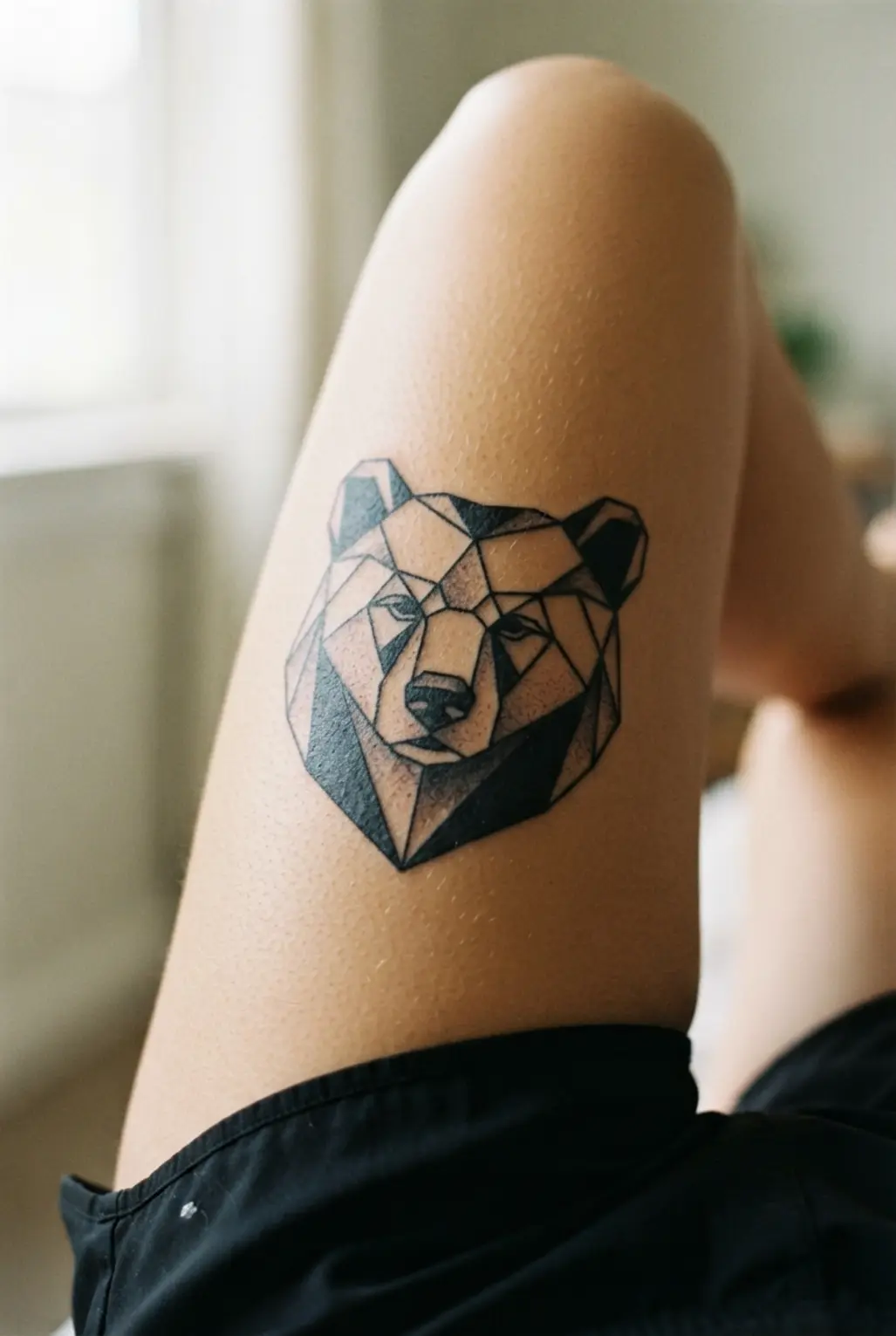 Black and white tattoo ideas featuring a geometric animal portrait on the thigh with angular planes and bold outlines.