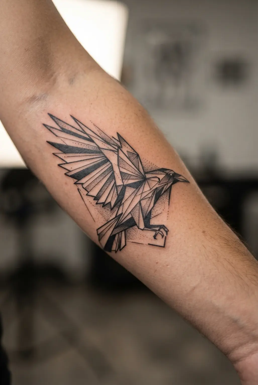 Abstract raven formed from sharp geometric lines and solid black shapes across a forearm in monochrome ink.
