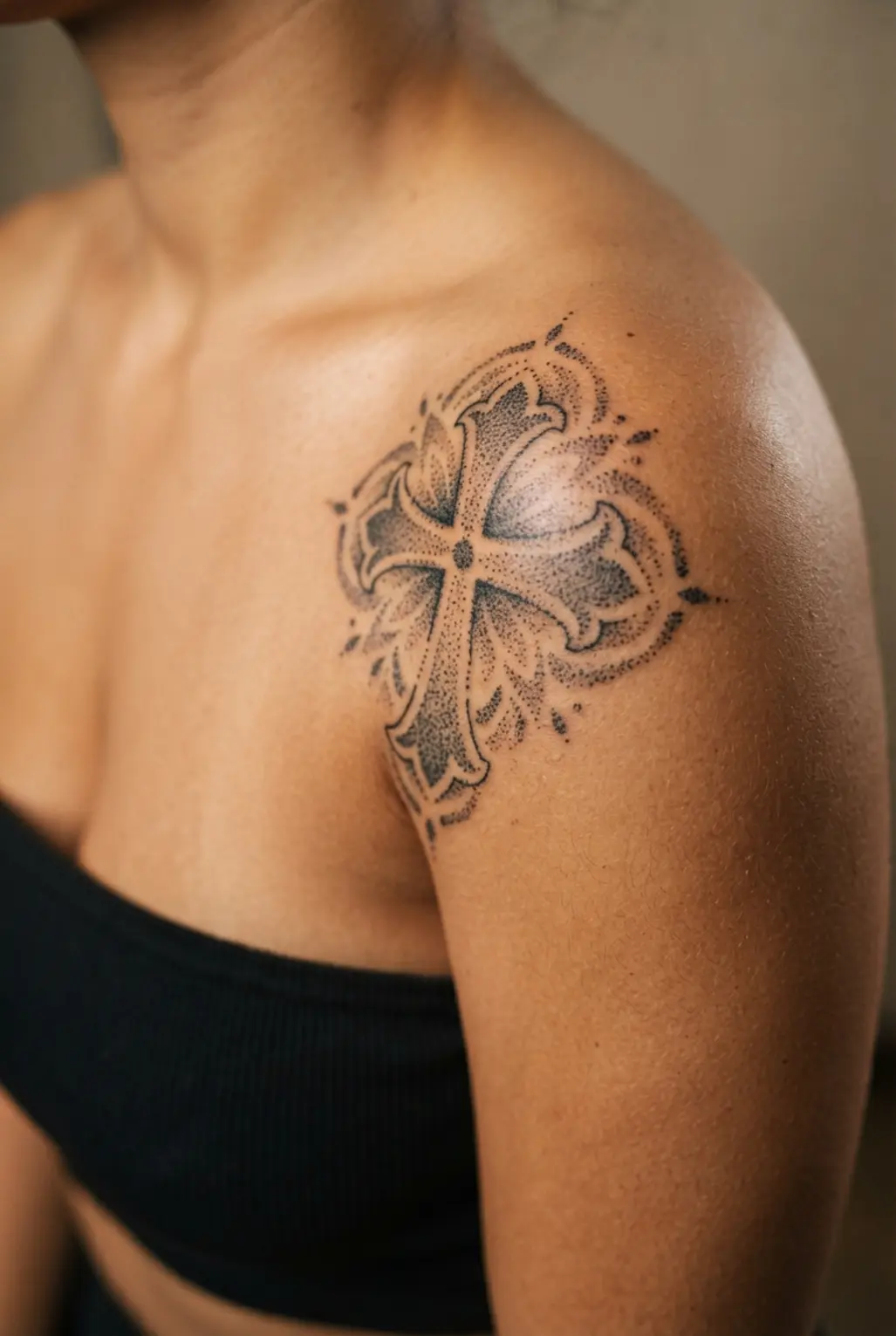 Stippled dotwork cross tattoos on shoulder with ornamental points and balanced black dots around the cap.
