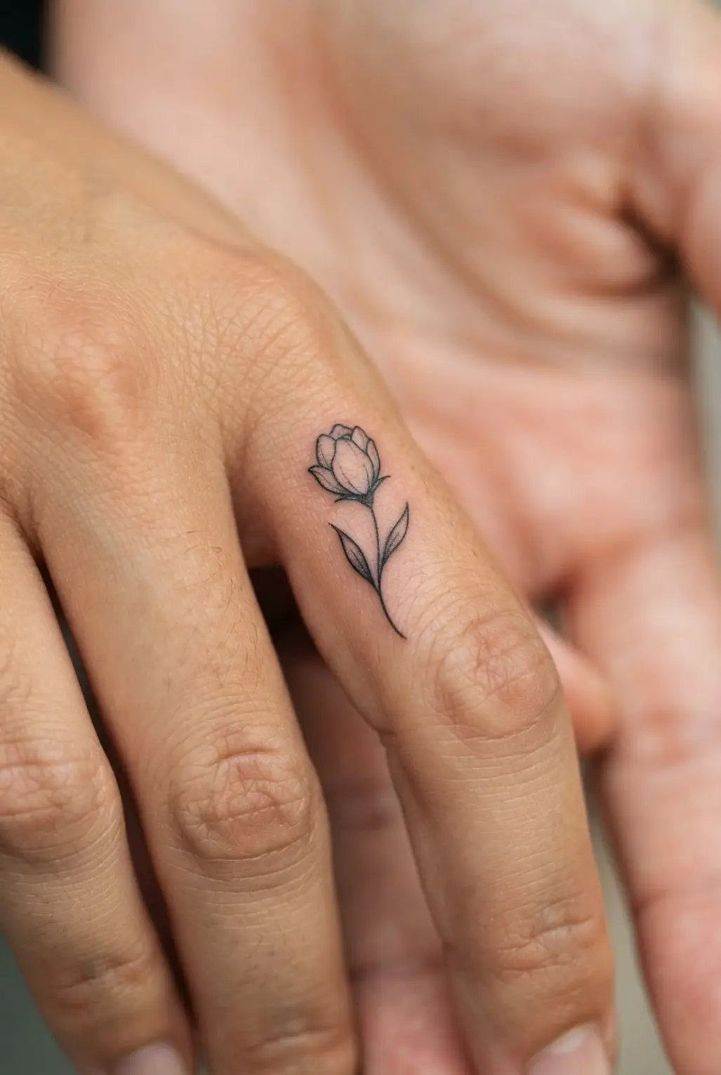 A dainty flower bud rests along a finger with a short stem, two leaves, and fine black contours.