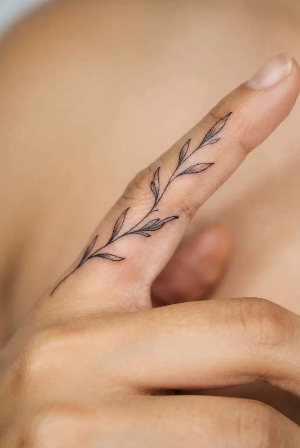 A small olive branch appears along a finger in clean black linework with spaced leaves and a slender stem.