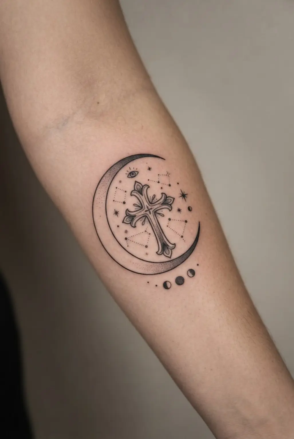 A crescent moon curves beside a black cross surrounded by stars, dots, and small celestial symbols.