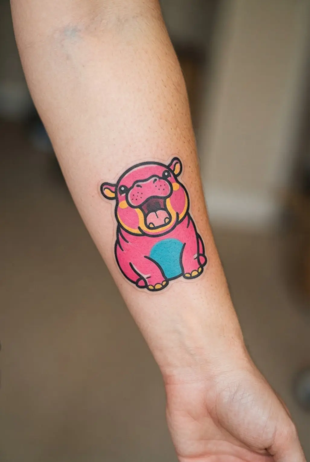 Moo Deng hippo tattoo showing an open-mouth scream, rounded cheeks, thick outlines, and bright sticker-style color.