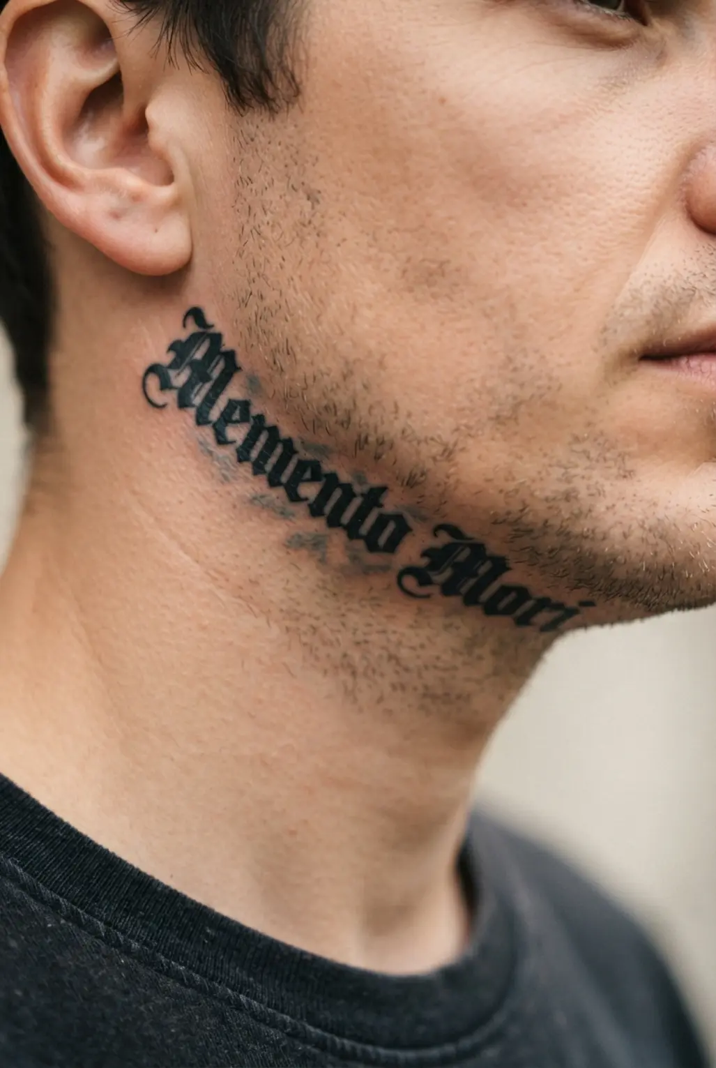 Classic black letter font tattoo running along the jawbone.