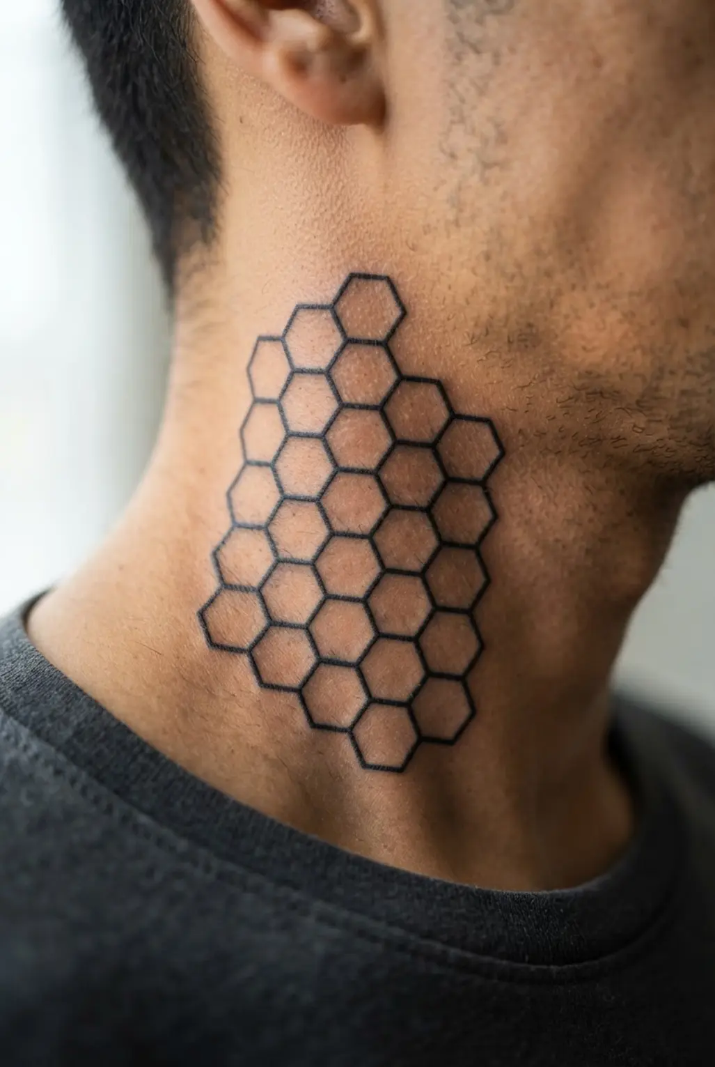 Geometric hexagon grid tattoo placed on the side of the neck.