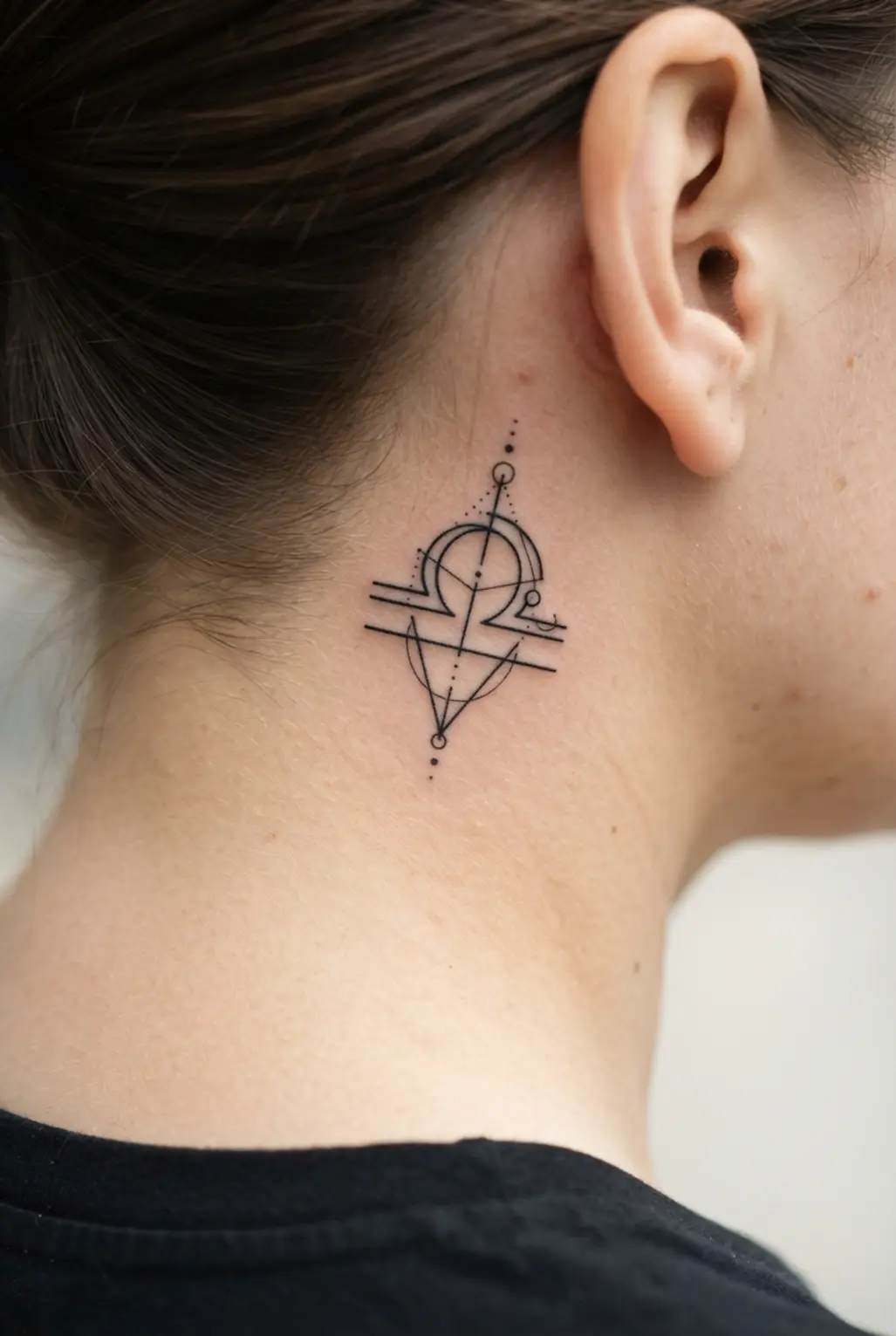 Minimalist geometric zodiac symbol behind the ear, shown as a clean neck tattoo idea for women in fine black lines.