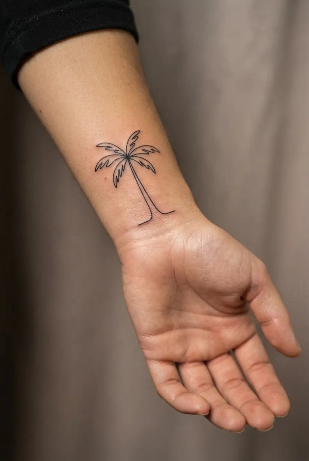 Palm tree tattoo ideas featuring one continuous black line forming a tropical palm on the wrist.