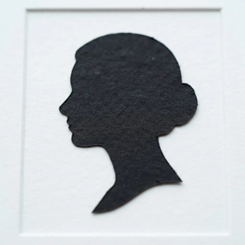 Black cardstock profile portrait with a clean silhouette and paper cutting design on a white background.