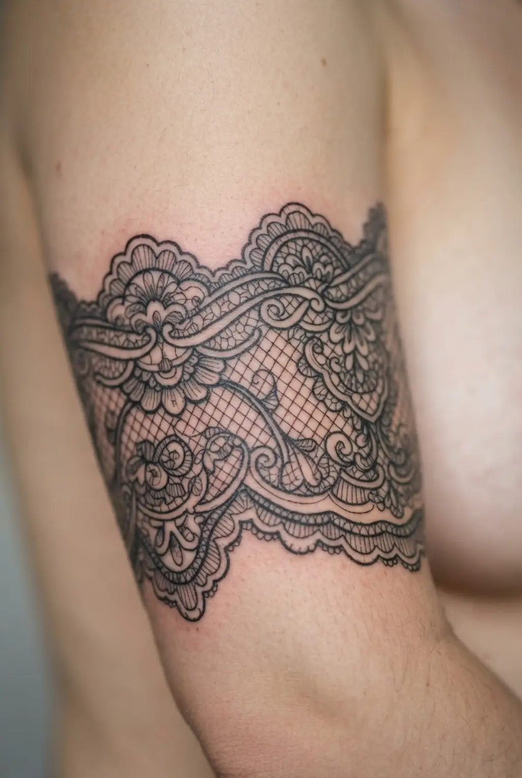 A delicate tattoo mimicking vintage lace patterns, creating a textured quarter sleeve effect.
