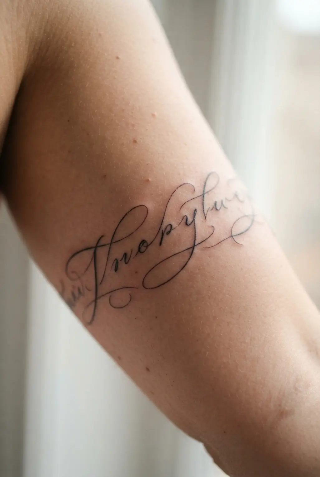 A personal script quote tattooed in delicate lettering along the inner arm, part of a cohesive quarter sleeve design.