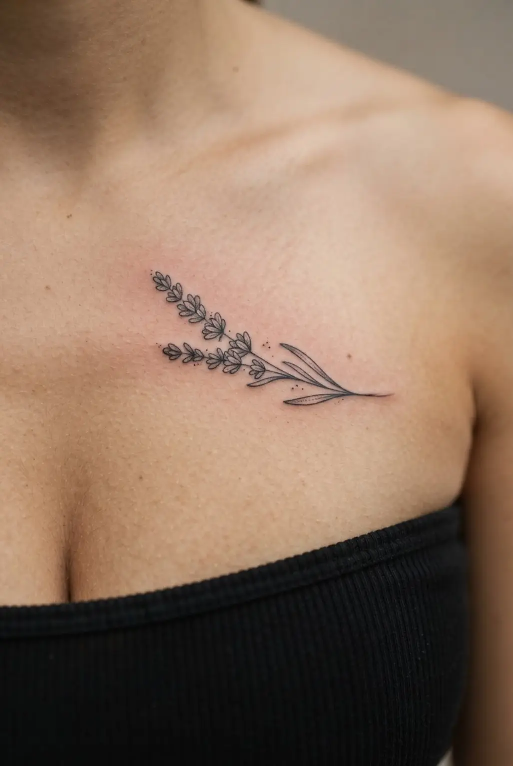 Small chest tattoos for women shown as a delicate lavender sprig below the collarbone.