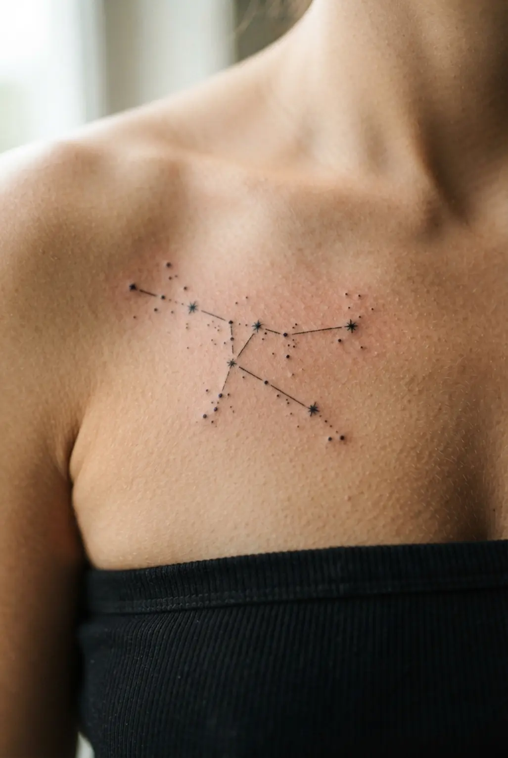 Fine-line black constellation dots and stars arranged across the upper chest in a balanced cluster.