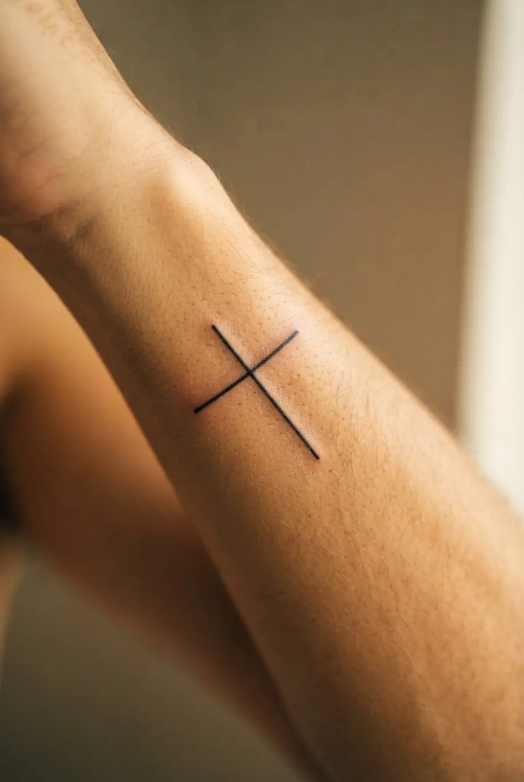 Horizontal cross along the outer forearm edge, showing a small cross tattoo for men in spare black lines.