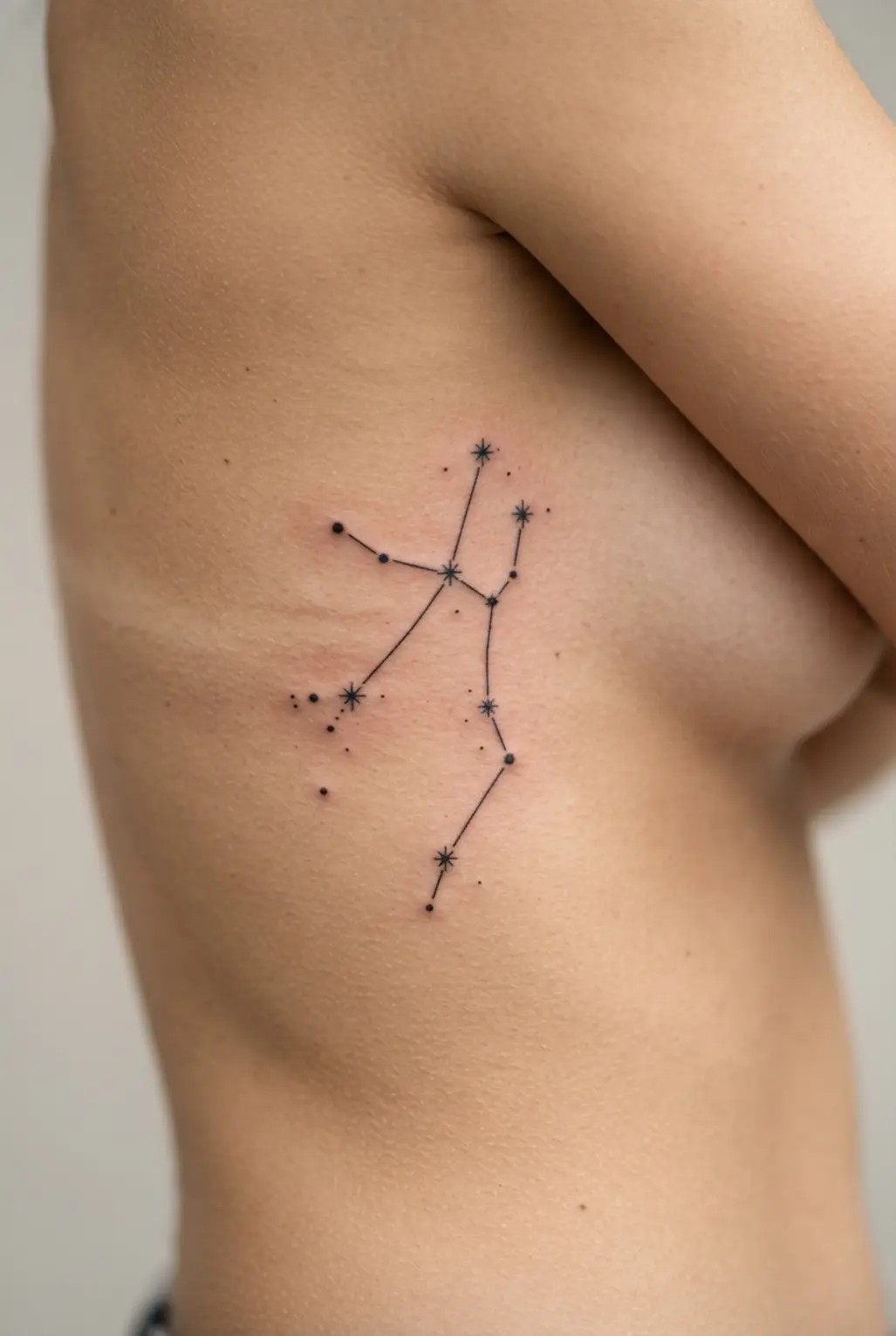 A flowing rib tattoo placing the Virgo constellation vertically along the side of the body.