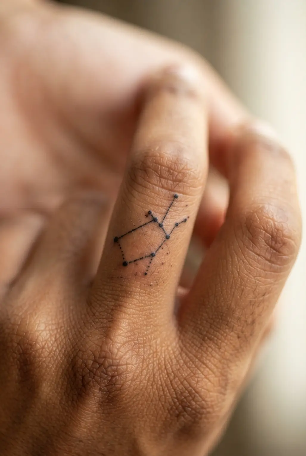 A subtle and tiny dotwork tattoo of the Virgo constellation placed on the side of a finger.