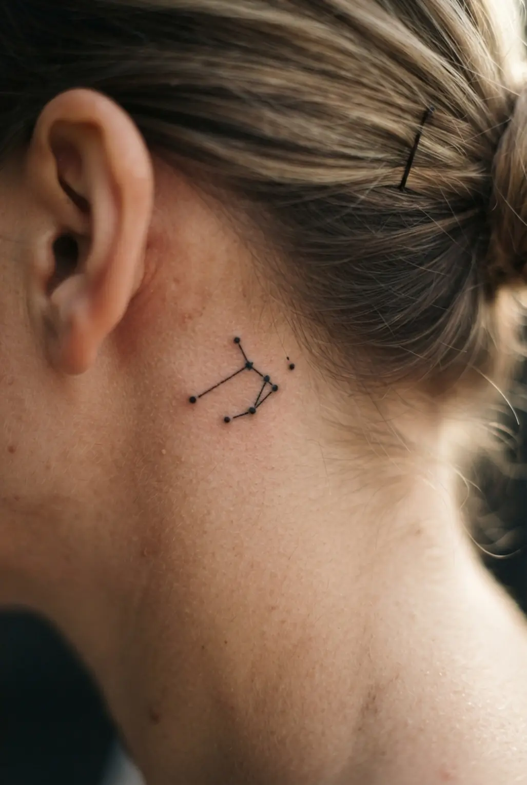 A discreet and personal tiny Virgo constellation tattoo placed behind the ear.