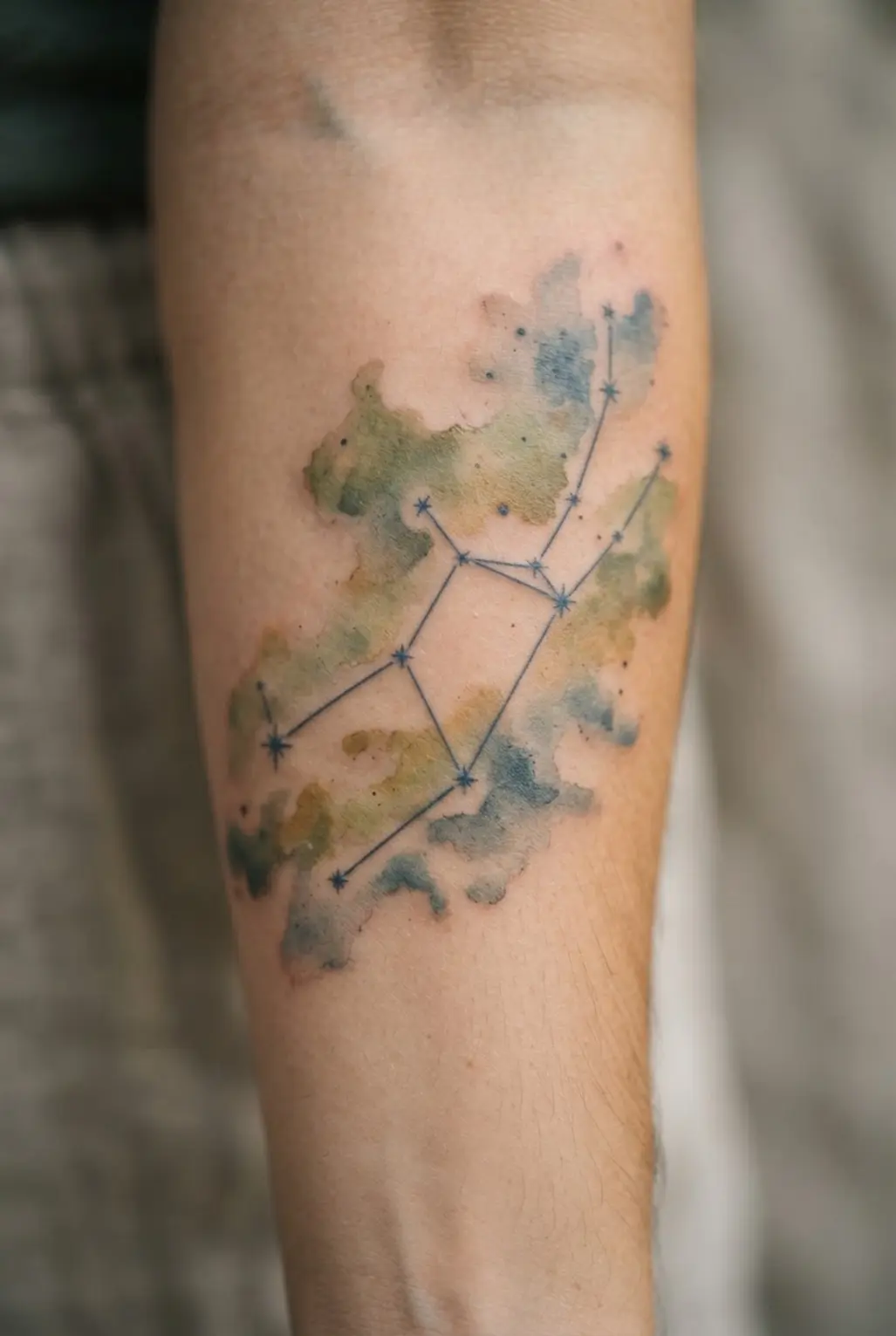 An earthy Virgo constellation tattoo design using muted watercolor tones of green and brown.