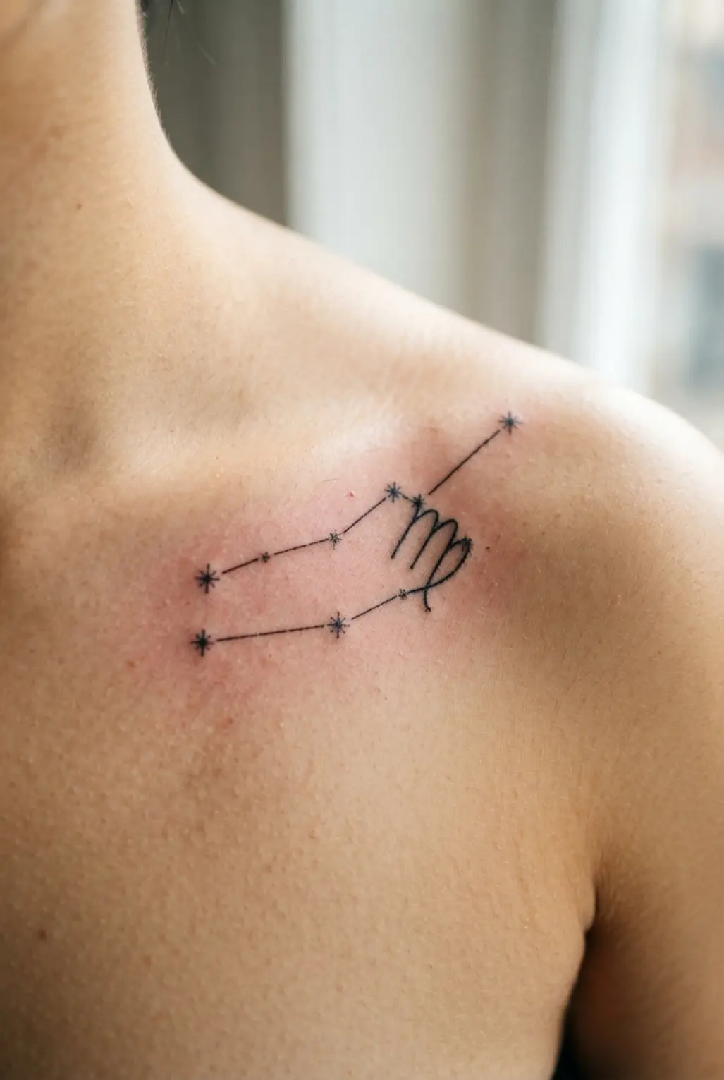 A graceful, horizontal fine-line tattoo of the Virgo constellation following the collarbone.
