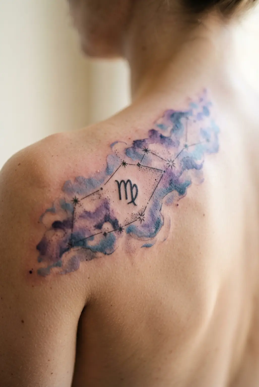 A celestial back piece featuring the Virgo stars amid soft blue and purple watercolor washes.