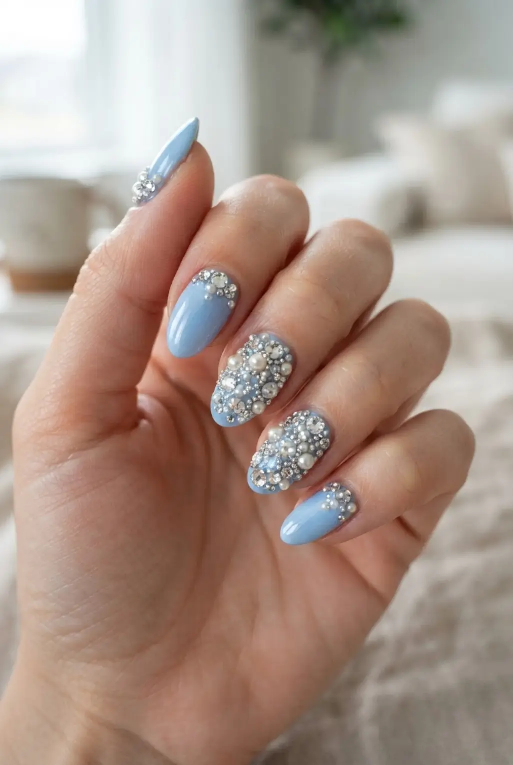 Light blue rhinestone nails with clear gems, pearl accents, and glossy blue polish.